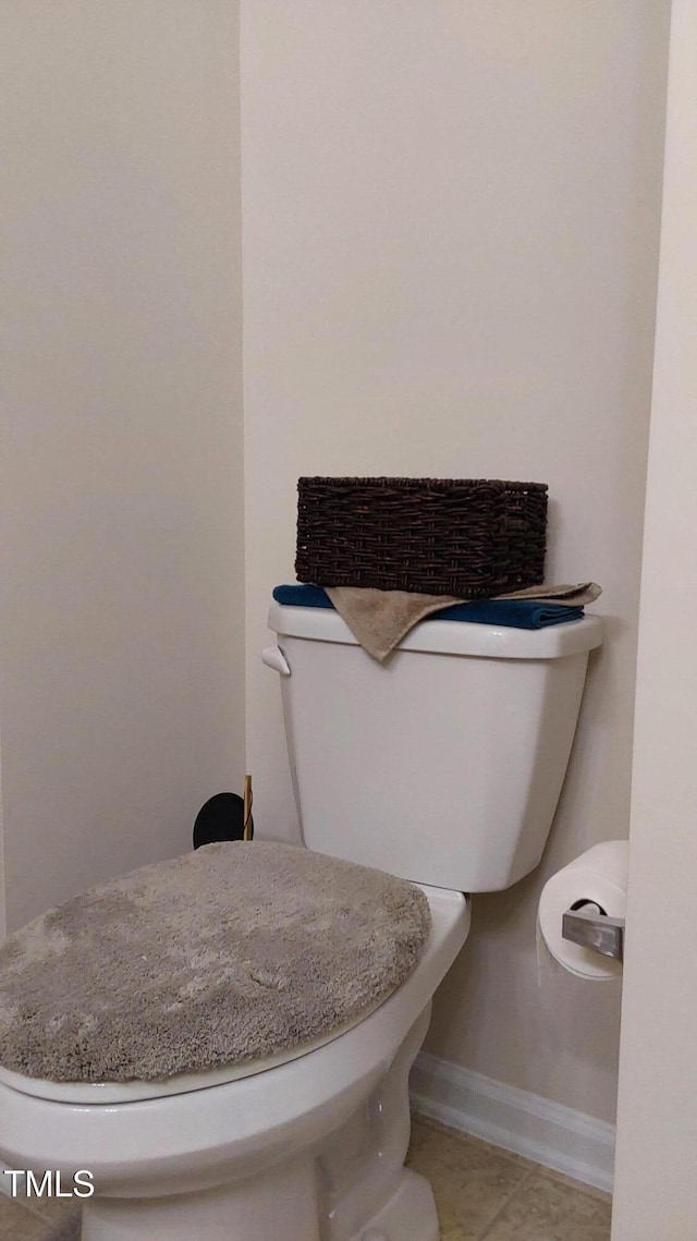 bathroom with toilet, baseboards, and tile patterned flooring