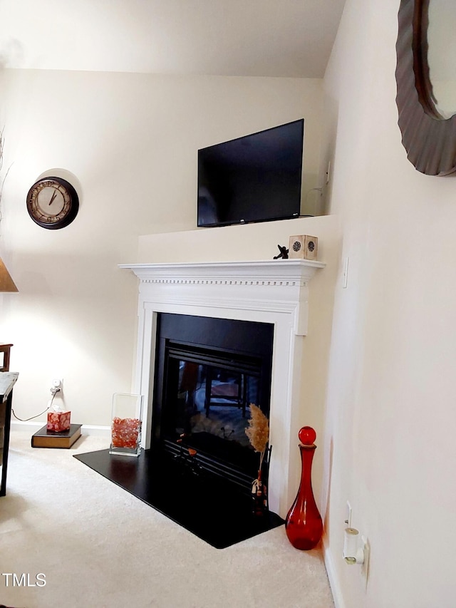 detailed view of carpet floors, a fireplace with flush hearth, and baseboards