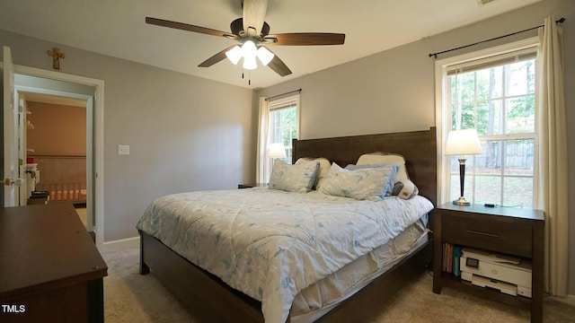 carpeted bedroom with multiple windows, a ceiling fan, and baseboards