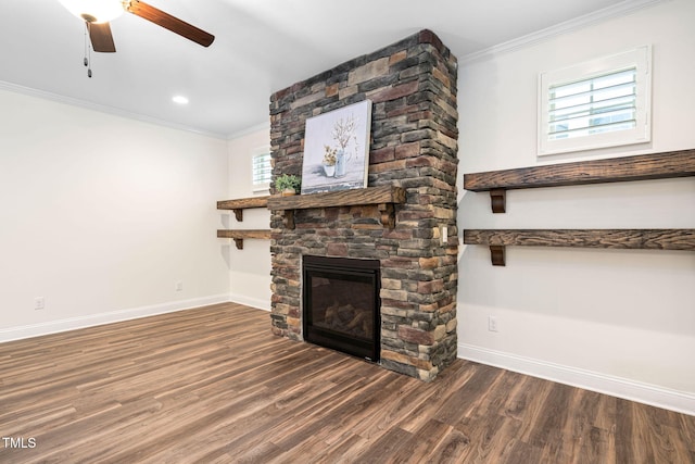 unfurnished living room featuring baseboards, crown molding, a stone fireplace, wood finished floors, and a ceiling fan
