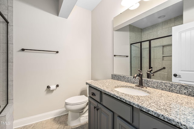 bathroom featuring baseboards, toilet, tiled shower, and vanity