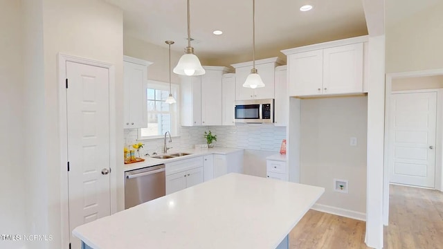 kitchen with appliances with stainless steel finishes, a sink, a center island, decorative backsplash, and light wood-style flooring