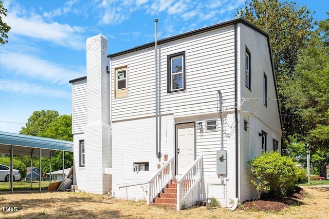 134 Nelson St, Durham, NC 27707 - back of property featuring entry steps, brick siding, a chimney, and a detached carport