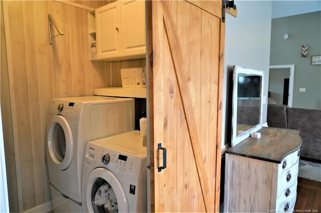 clothes washing area featuring cabinet space, washing machine and dryer, and a barn door