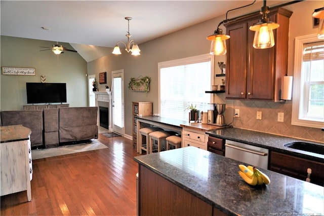 kitchen featuring stainless steel dishwasher, decorative backsplash, a ceiling fan, wood finished floors, and a fireplace