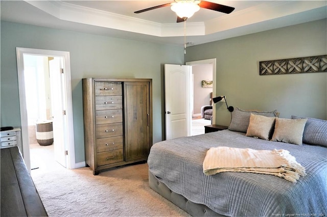 bedroom featuring a raised ceiling, ornamental molding, light carpet, ceiling fan, and connected bathroom
