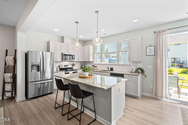 150 Gosford Ln, Garner, NC 27529 - kitchen with stainless steel appliances, a breakfast bar area, a kitchen island, light wood finished floors, and recessed lighting