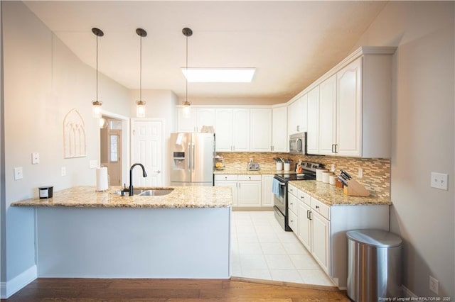 3119 Metthame Dr, Fayetteville, NC 28306 - kitchen featuring appliances with stainless steel finishes, a peninsula, tasteful backsplash, light stone counters, and hanging light fixtures