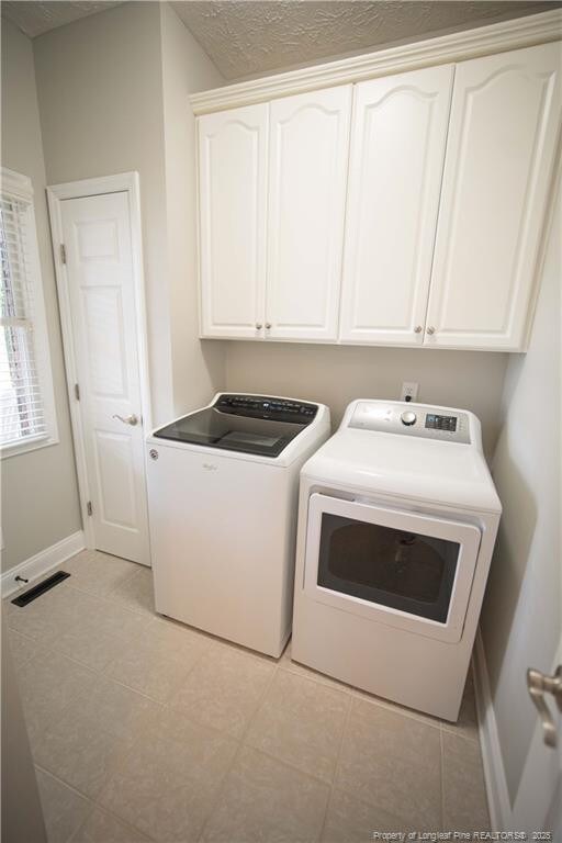 3119 Metthame Dr, Fayetteville, NC 28306 - washroom featuring washer and clothes dryer, cabinet space, and light tile patterned floors