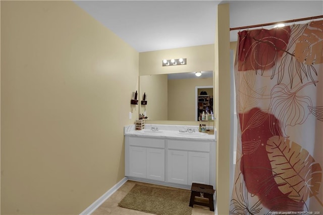 full bath featuring baseboards, double vanity, and tile patterned flooring