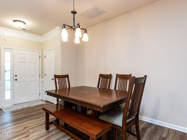 dining area with wood finished floors, a chandelier, ornamental molding, and baseboards