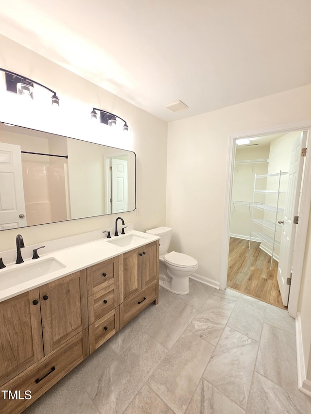 4206 Camden Woods Ct, Raleigh, NC 27612 - full bathroom featuring double vanity, toilet, a walk in closet, and baseboards