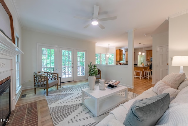 104 Tutbury Pl, Cary, NC 27519 - living room featuring light wood-style flooring, ornamental molding, ceiling fan, baseboards, and a brick fireplace