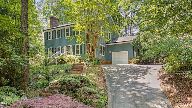 colonial-style house featuring a garage, concrete driveway, and a chimney