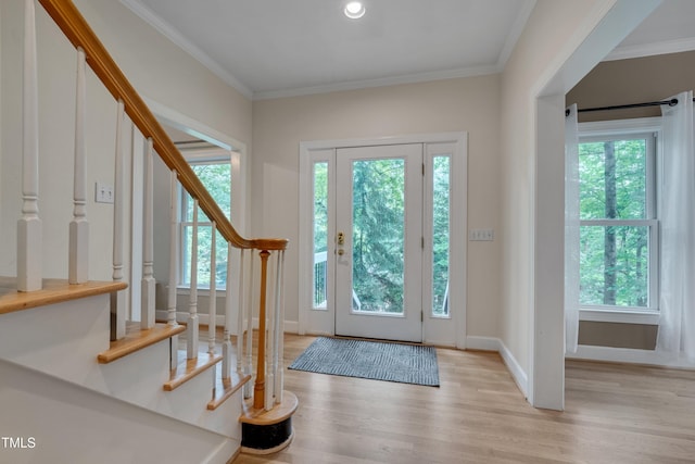 foyer entrance with plenty of natural light, stairway, wood finished floors, ornamental molding, and baseboards