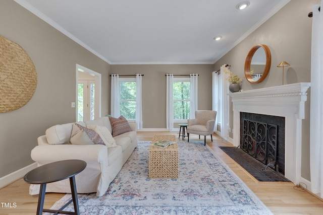 living room featuring wood finished floors, ornamental molding, baseboards, a fireplace with flush hearth, and recessed lighting