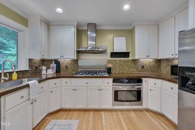 kitchen featuring stainless steel appliances, wall chimney exhaust hood, light wood-type flooring, white cabinets, and recessed lighting