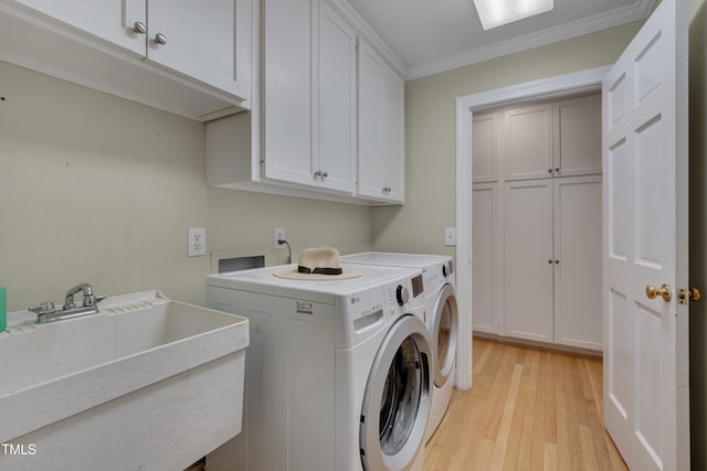 laundry room featuring cabinet space, separate washer and dryer, crown molding, and light wood-style floors