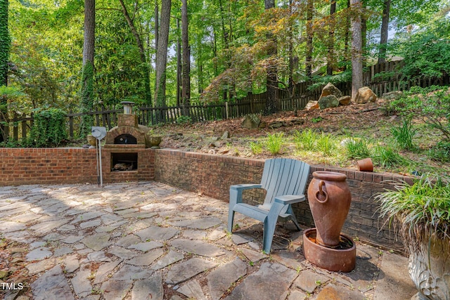 view of patio / terrace with an outdoor brick fireplace and a fenced backyard