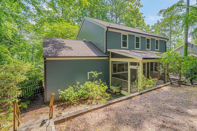 rear view of property featuring a sunroom and a shingled roof