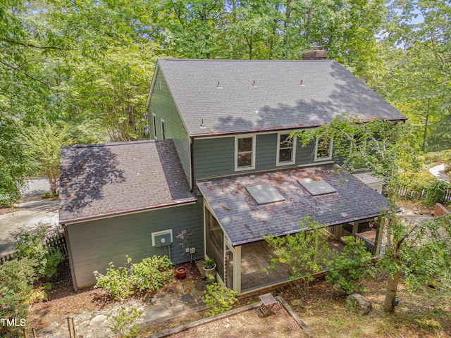 back of property with roof with shingles and a chimney