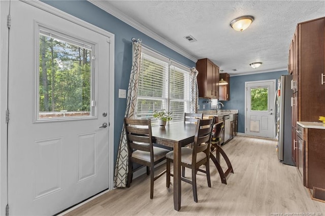 5712 Icarus Cir, Fayetteville, NC 28304 - dining space with light wood-style floors, ornamental molding, a textured ceiling, and baseboards
