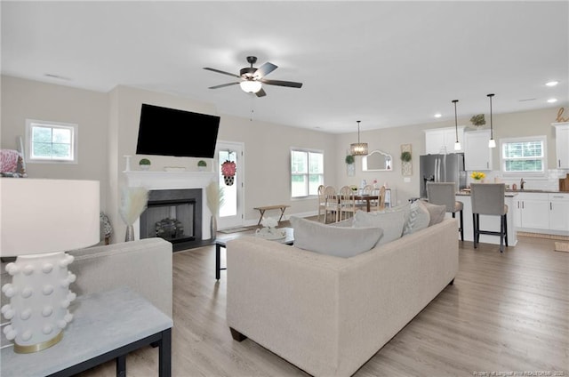 5831 James Allen Ln, Stedman, NC 28391 - living room featuring plenty of natural light, a fireplace with flush hearth, light wood-style flooring, recessed lighting, and ceiling fan