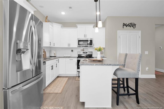5831 James Allen Ln, Stedman, NC 28391 - kitchen with stainless steel appliances, a kitchen island, a breakfast bar, light wood-type flooring, and light stone counters