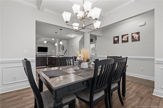dining room with dark wood-style floors, crown molding, a chandelier, and wainscoting