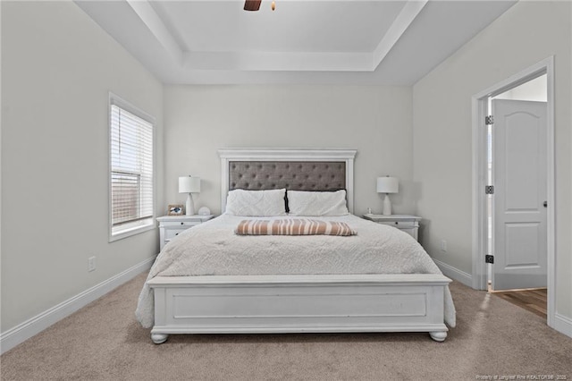 bedroom with carpet, baseboards, a tray ceiling, and a ceiling fan