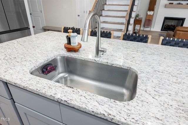 220 Purslane Dr, Franklinton, NC 27525 - kitchen view of a sink, light stone counters, a large fireplace, and gray cabinets