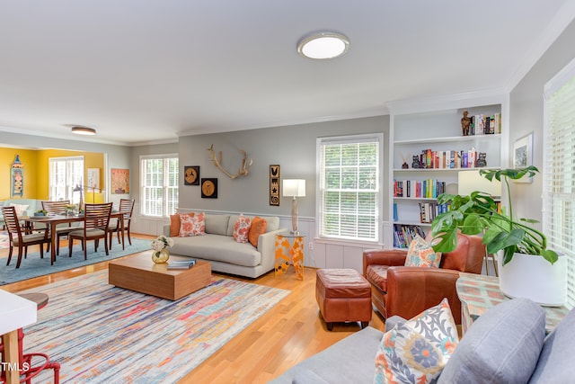 living room featuring wood finished floors, crown molding, and a wainscoted wall