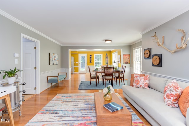living area with light wood-style floors, ornamental molding, and wainscoting
