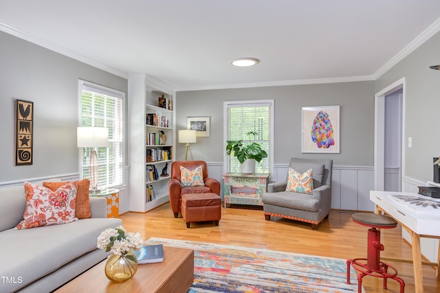 living area with wood finished floors, plenty of natural light, ornamental molding, built in features, and a wainscoted wall
