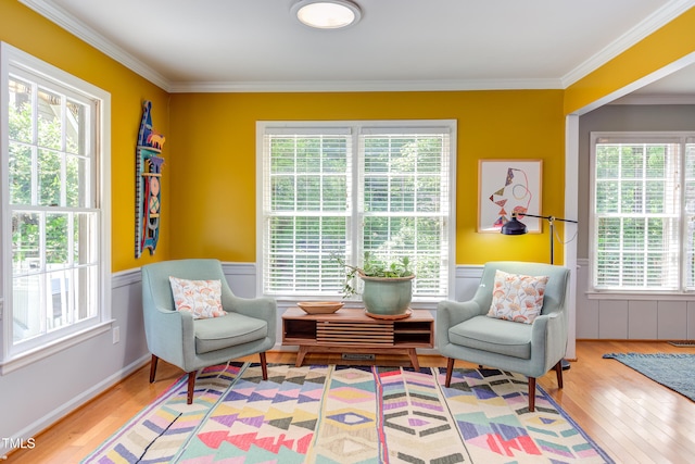 sitting room featuring ornamental molding, healthy amount of natural light, wood finished floors, and wainscoting