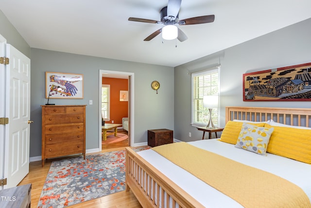 bedroom with light wood finished floors, multiple windows, and baseboards