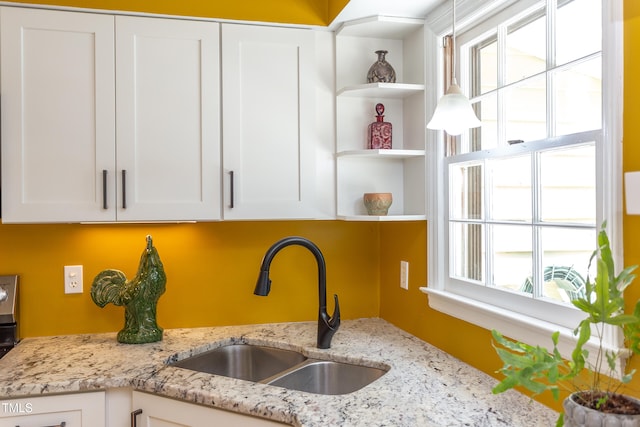 kitchen featuring a sink, open shelves, white cabinets, and light stone counters
