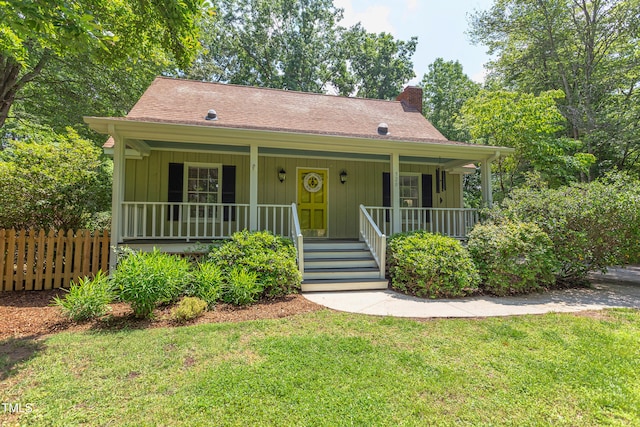 view of front of home featuring a chimney, a porch, and a shingled roof