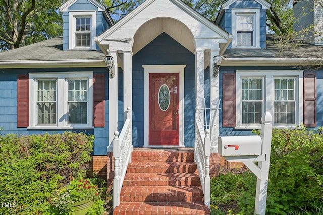 view of exterior entry featuring roof with shingles