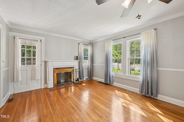 unfurnished living room with plenty of natural light, light wood-style flooring, a fireplace with flush hearth, and ornamental molding