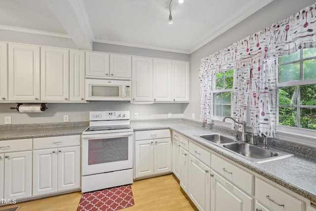 kitchen with white appliances, a sink, healthy amount of natural light, crown molding, and white cabinets