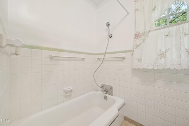 bathroom featuring tile walls, shower / tub combination, and a wainscoted wall