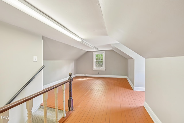 additional living space with hardwood / wood-style flooring, baseboards, and lofted ceiling