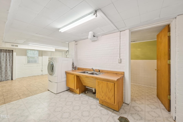 laundry room with light floors, wainscoting, and brick wall