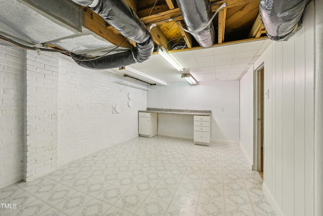 unfinished basement featuring light flooring and brick wall