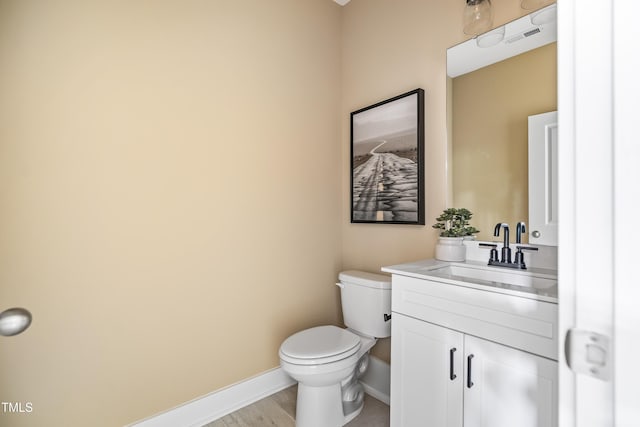 half bathroom featuring toilet, baseboards, vanity, and wood finished floors