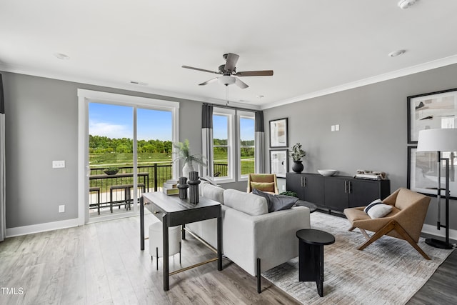living room featuring ceiling fan, light wood-type flooring, ornamental molding, and baseboards