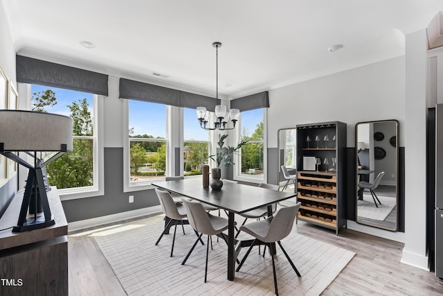 dining area featuring a chandelier, baseboards, wood finished floors, and ornamental molding
