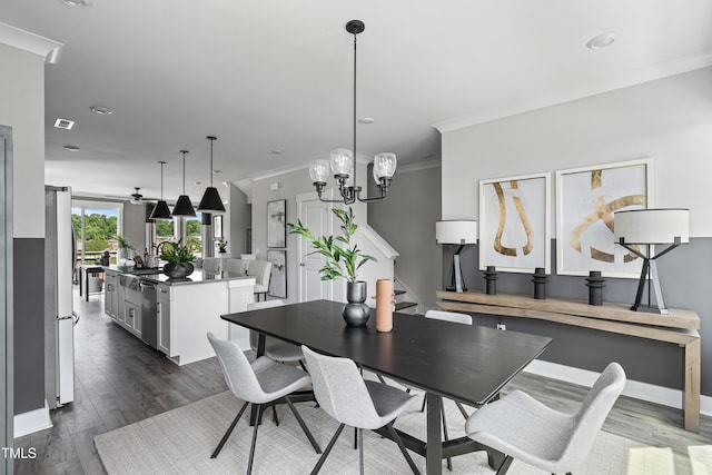 dining area with ornamental molding, dark wood finished floors, stairway, a ceiling fan, and a chandelier