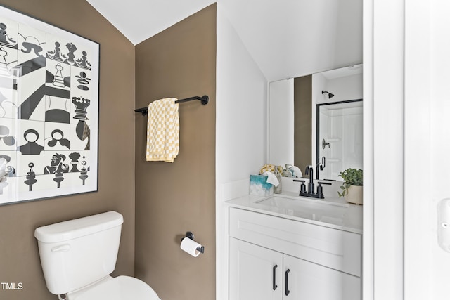 bathroom with toilet, vaulted ceiling, and vanity